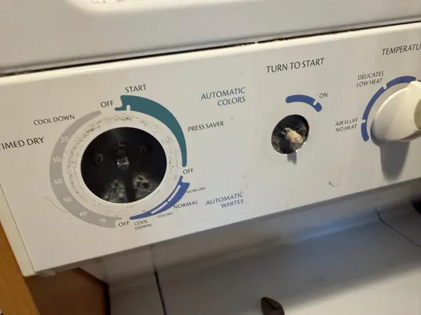 Dryer control panel with the timer and start knobs removed, showing the control shafts