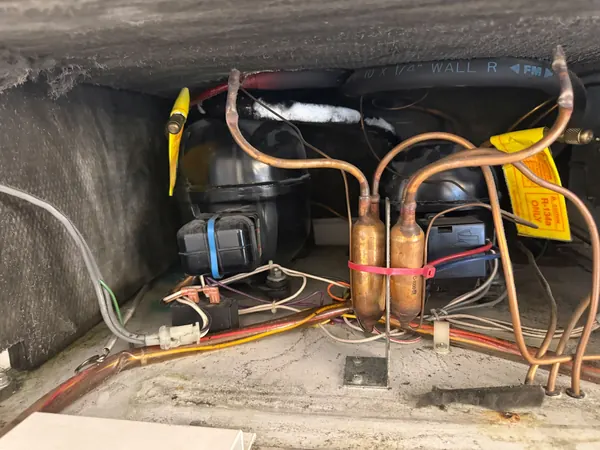 Refrigerator compressor compartment with copper refrigerant lines, filter driers and an R-134a service tag