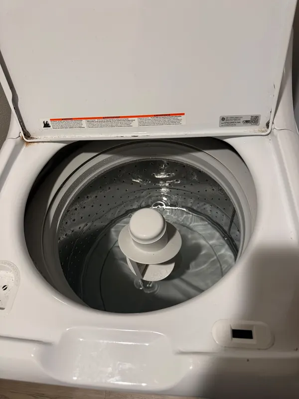 Top-load washing machine with the lid open, showing the drum and the agitator